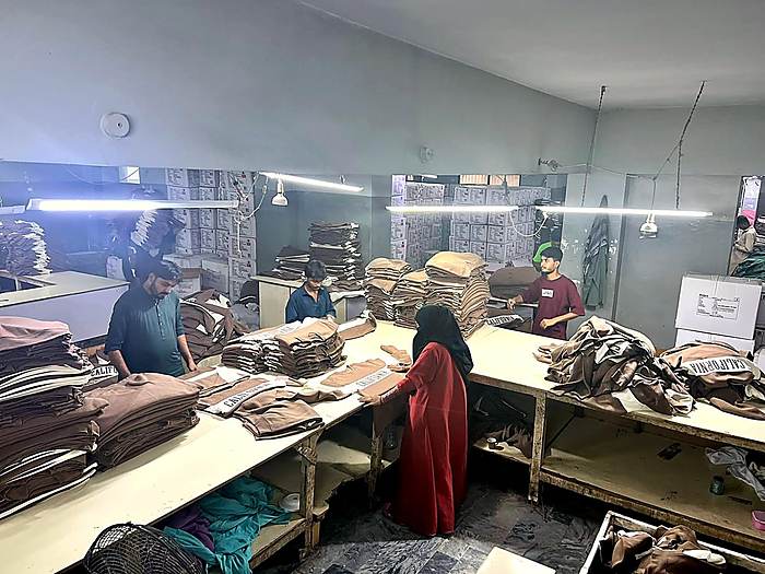 Worker pressing a finished garment at Fine Apparels