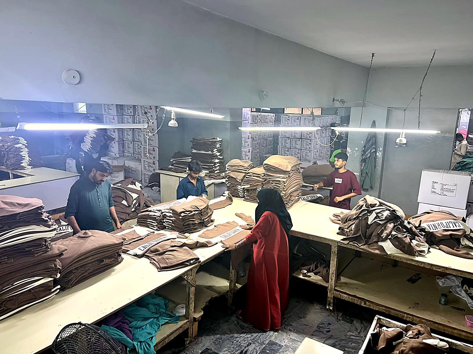 Worker pressing a finished garment at Fine Apparels